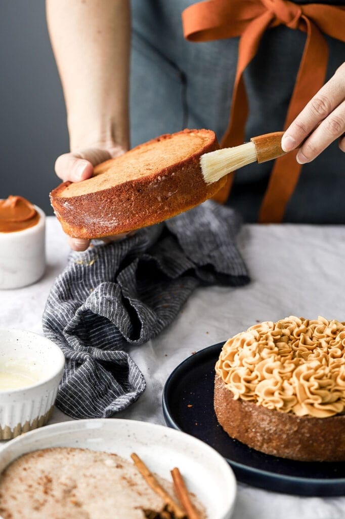 brushing melted butter onto cake