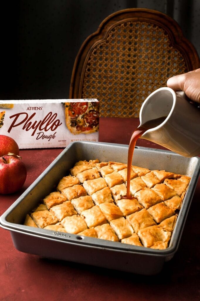 pouring apple syrup over baklava