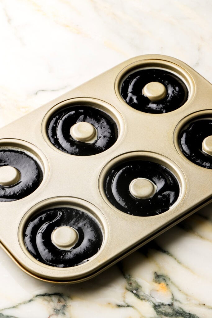 chocolate donut batter piped into donut molds