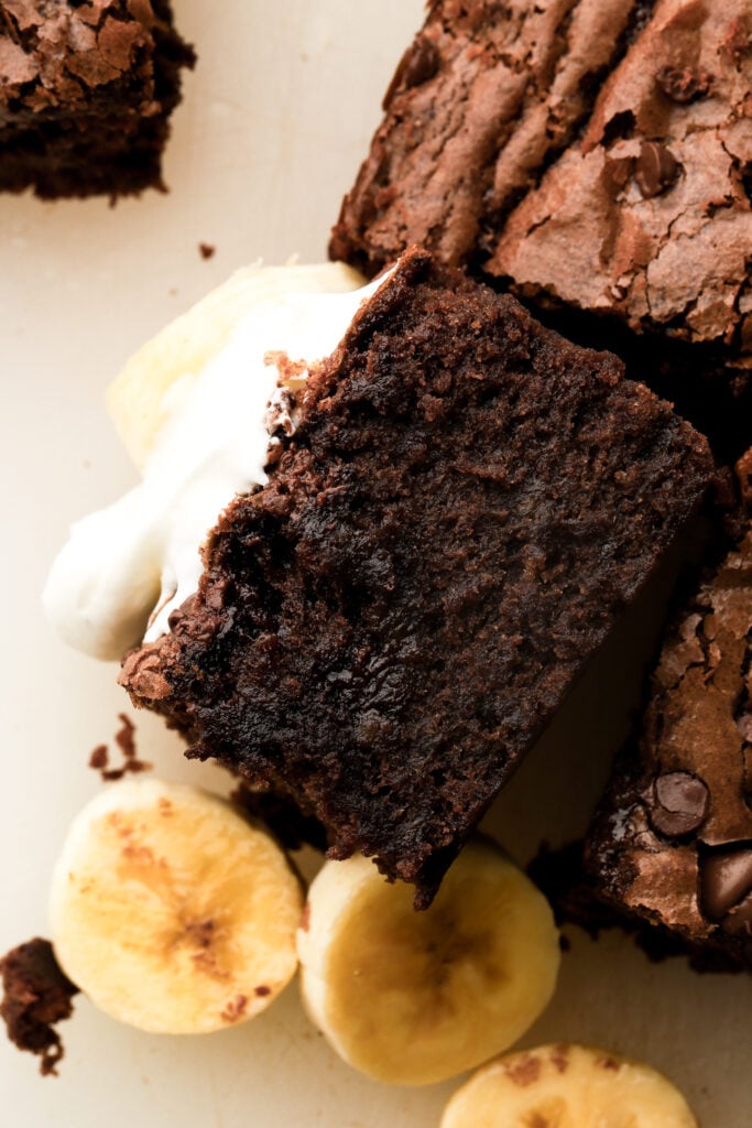 close up of banana brownies topped with whipped cream.
