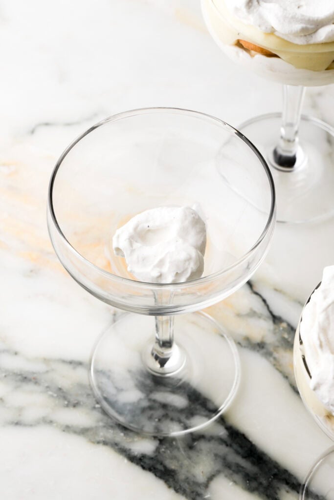 first layer of whipped cream on the bottom of a coupe glass