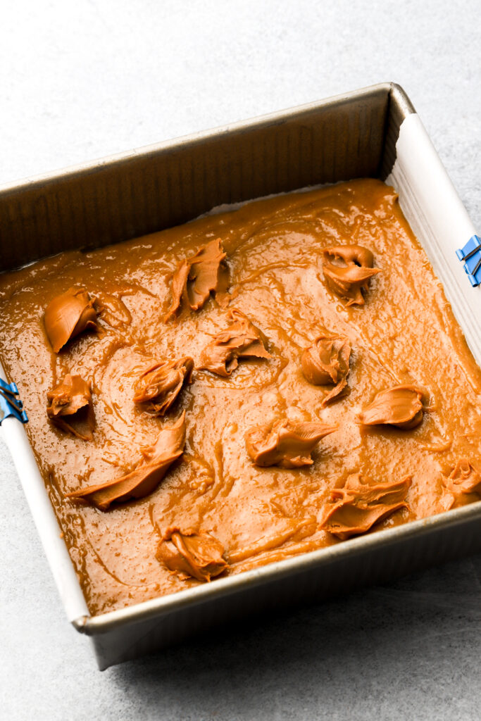 half of the batter spread into the pan with cookie butter globs