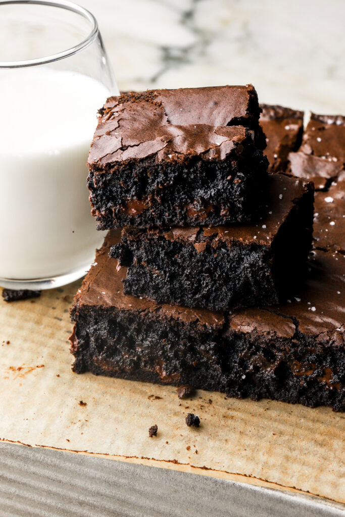 black cocoa brownies with a cup of milk next to them.