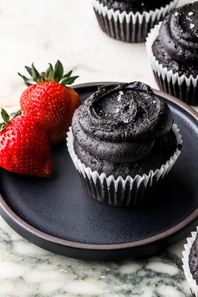 black cocoa cupcakes on a plate served with fresh fruit