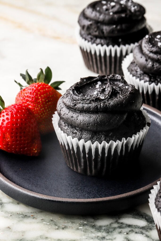 black cocoa cupcakes on a plate served with fresh fruit