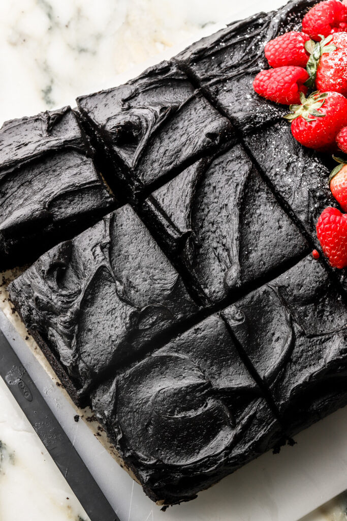 black cocoa sheet cake sliced with fruit on top