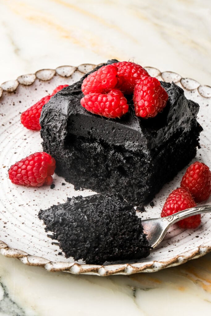 slice of black cocoa sheet cake on a plate with a bite taken out