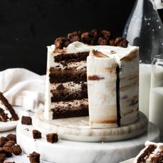 brownie cake frosted with cream cheese frosting, a slice removed and little brownies and milk on the side