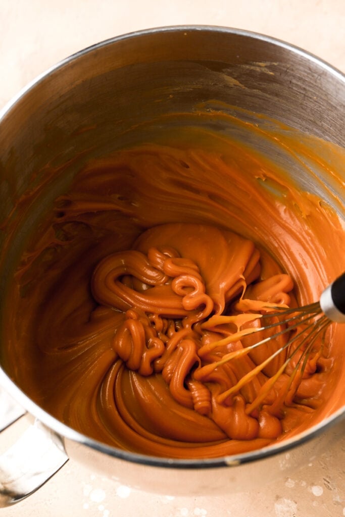butterscotch ganache cooled in a bowl with the whisk