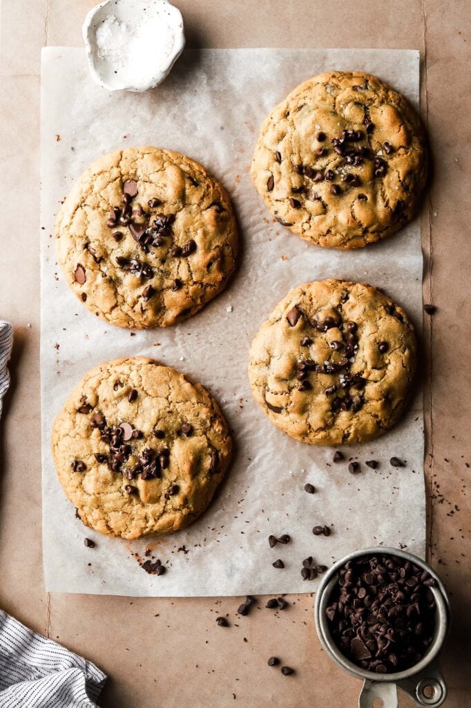 four baked cookies with extra chocolate chips on top and sea salt