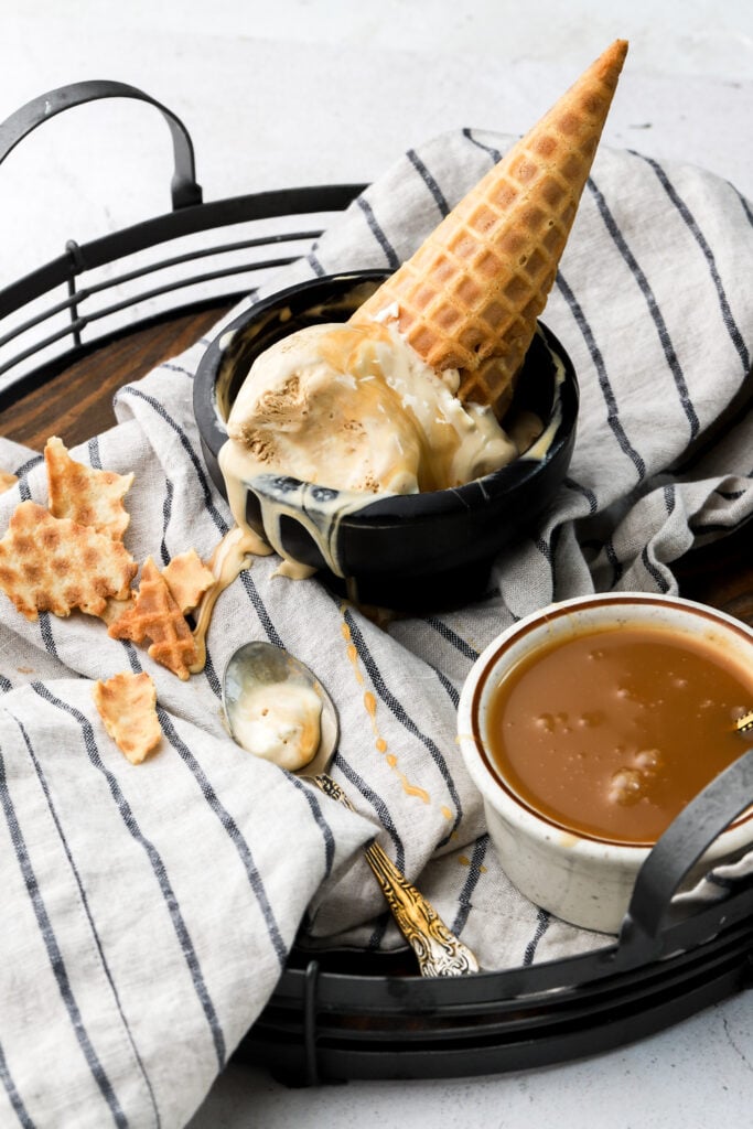ice cream in a bowl with a cone on a tray with caramel sauce