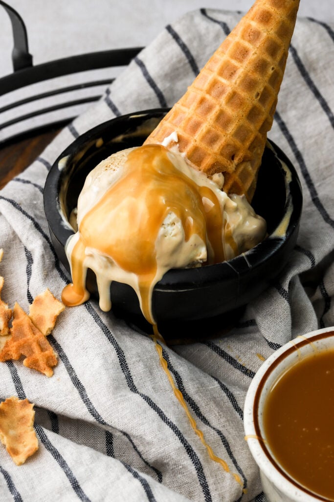 caramel macchiato ice cream in a bowl with a cone and caramel sauce on top