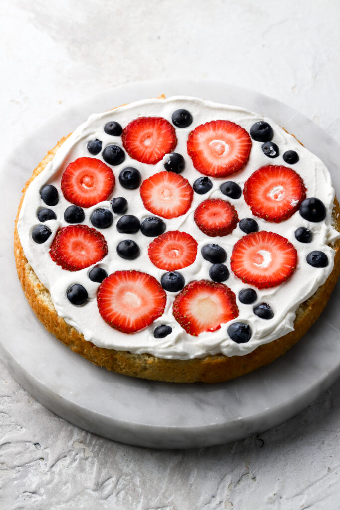 assembling the cake with chantilly cream and berries