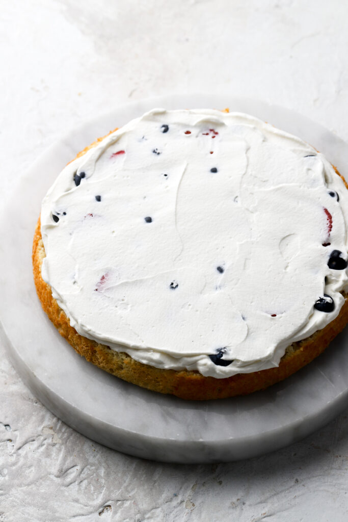 assembling the cake with chantilly cream and berries