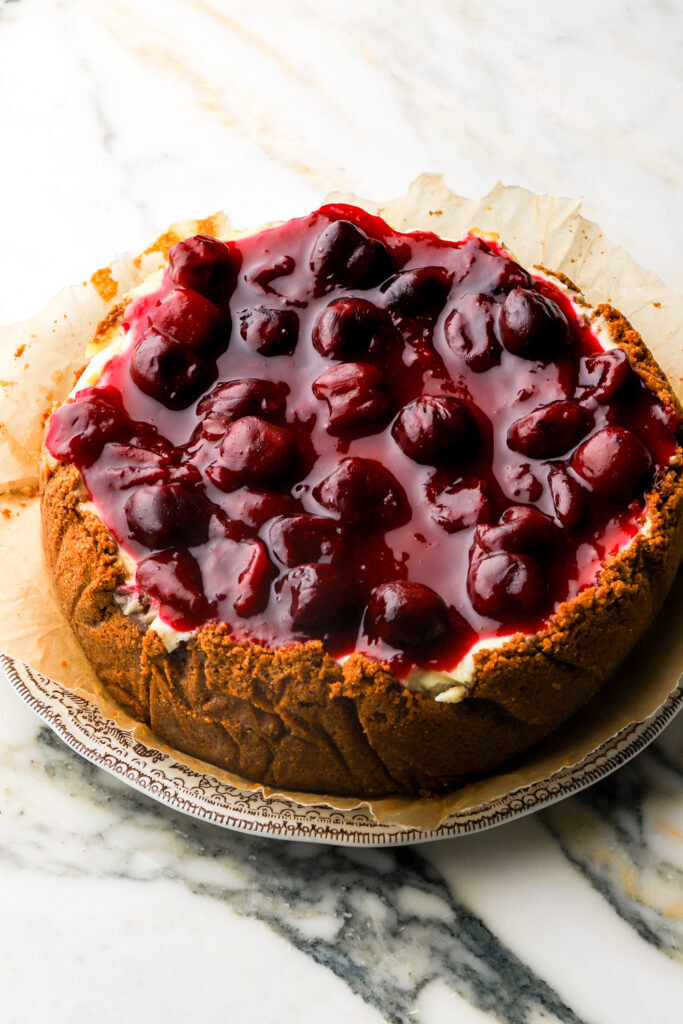 cherry topping spread on top of cooled cheesecake