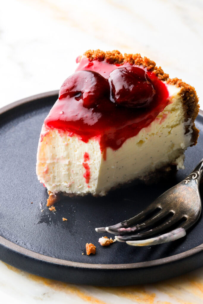 slice of cherry cheesecake on a plate with a bite taken out