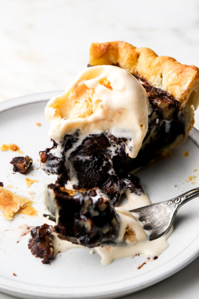slice of chocolate pecan pie on a plate with ice cream