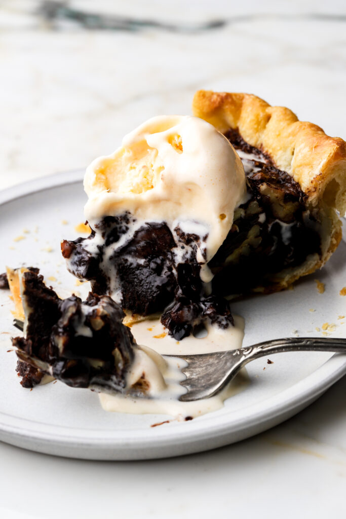 slice of chocolate pecan pie on a plate with a bite taken out