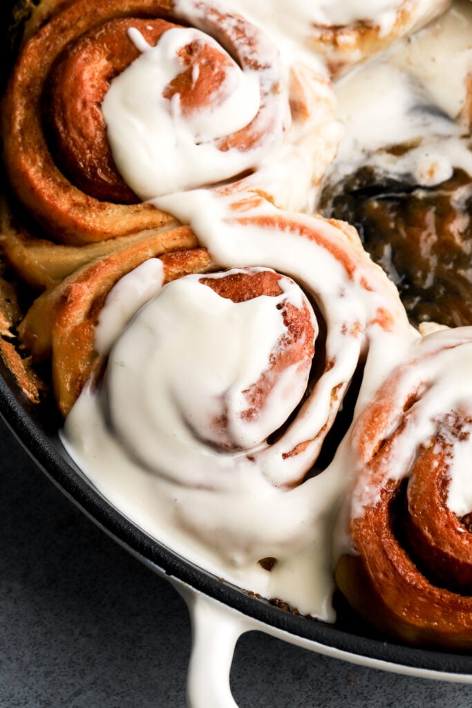 close up of cinnamon rolls in a pan with cream cheese frosting