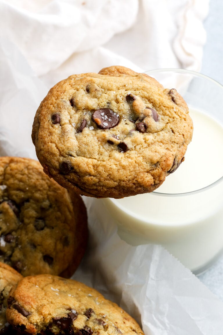 chocolate chip cookie sitting on a cup of milk