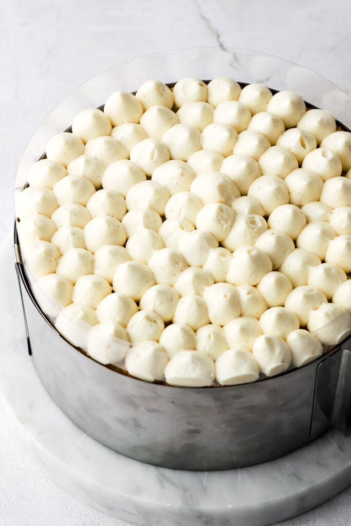 pipe poofs of crème mousseline on top of the cake