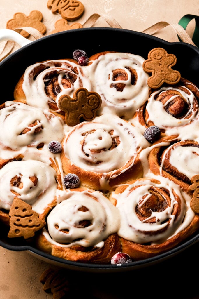 Gingerbread cinnamon rolls in a pan with icing on top