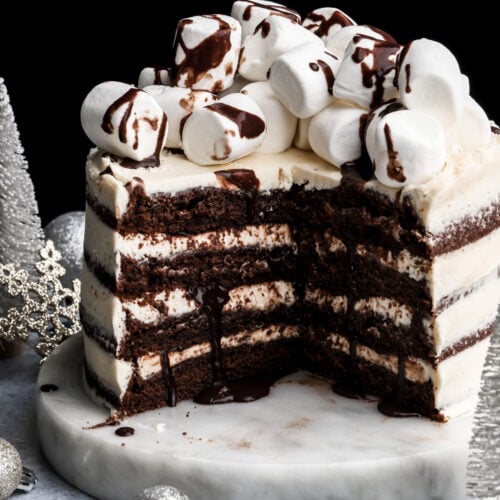 hot chocolate cake topped with marshmallows and chocolate fudge sauce with a few slices removed