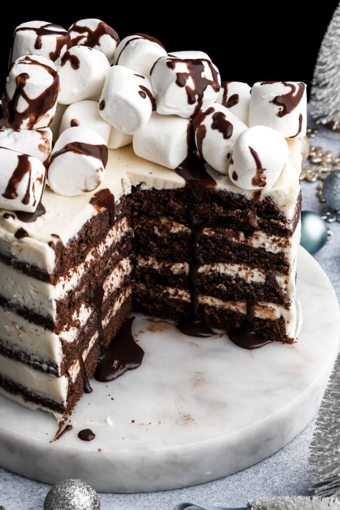 hot chocolate cake topped with marshmallows and chocolate fudge sauce with a few slices removed