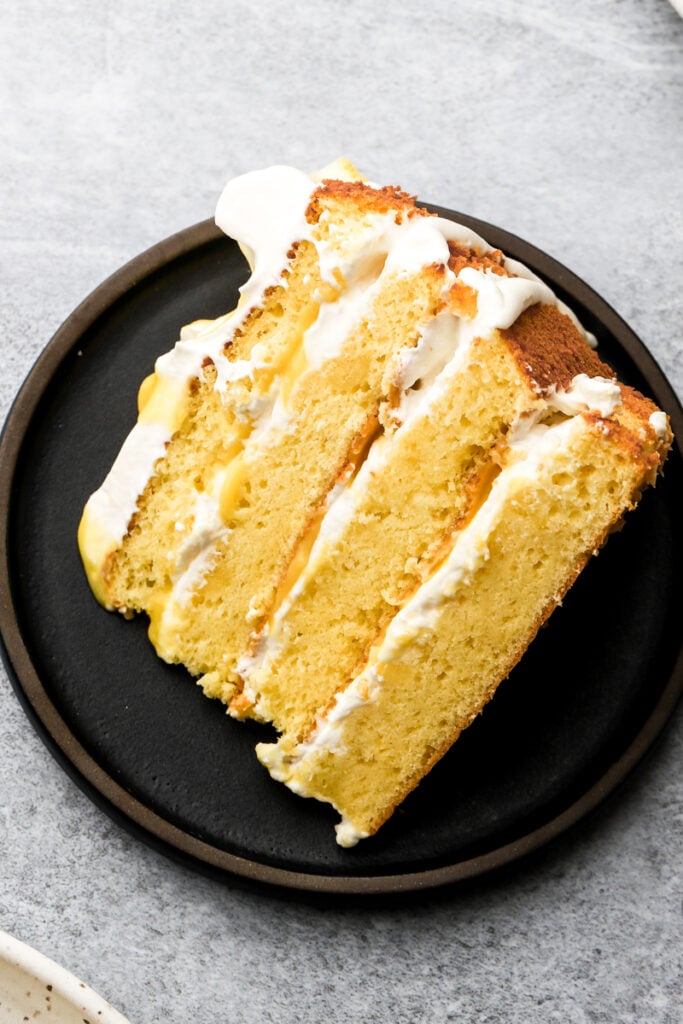molly cake with whipped cream and lemon curd on a dark plate