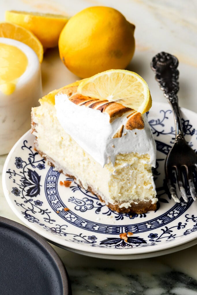 slice of lemon meringue cheesecake on a plate with a bite taken out