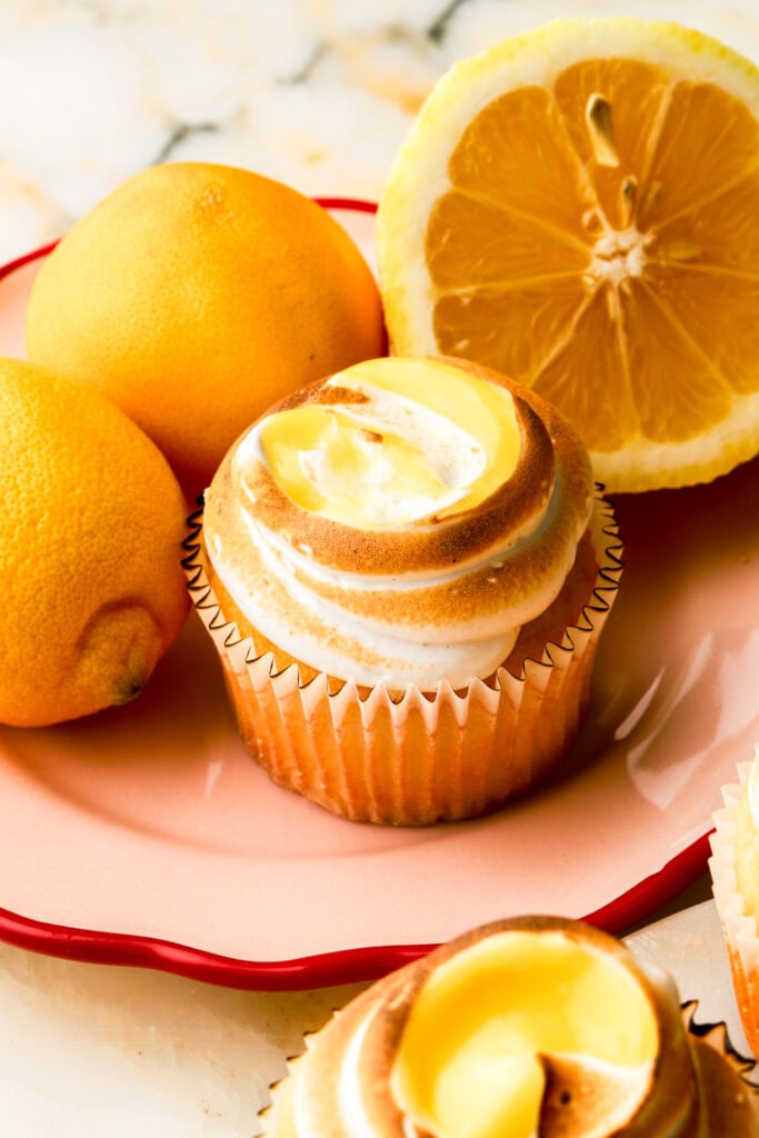lemon meringue cupcakes in a plate with lemons