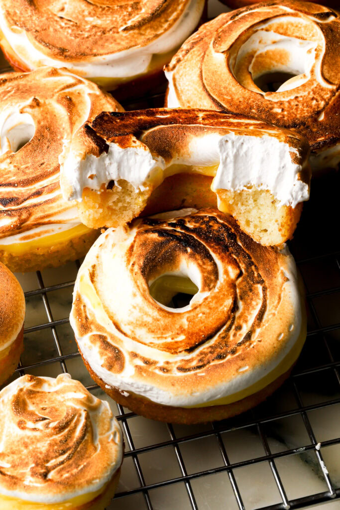 close up of baked lemon meringue donuts with two bites taken out