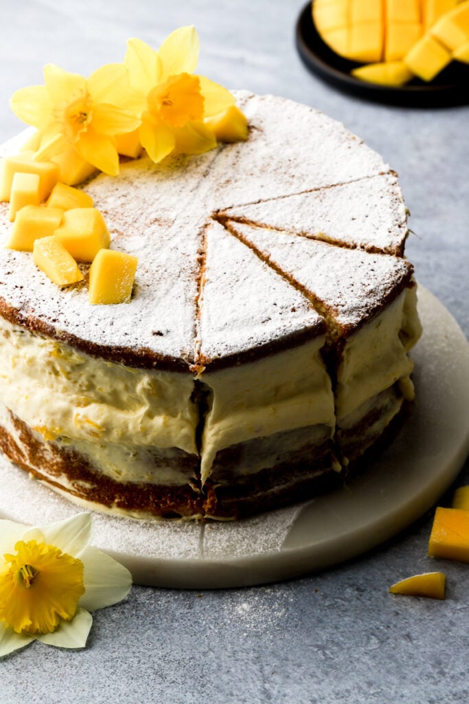 mango cake topped with fresh mangos and flowers