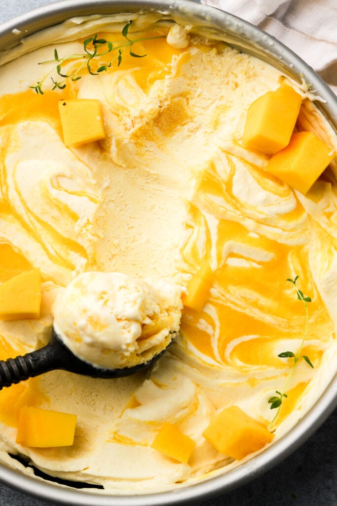 Mango ice cream with mango puree swirls and an ice cream scooper