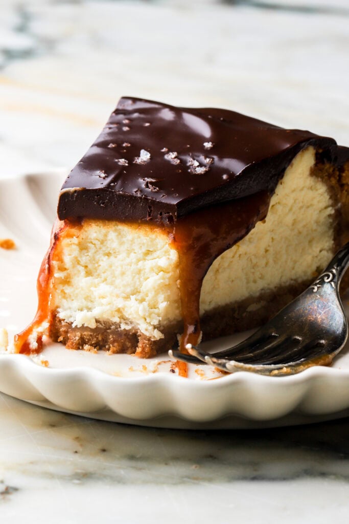 slice of millionaire cheesecake on a plate with a bite taken out