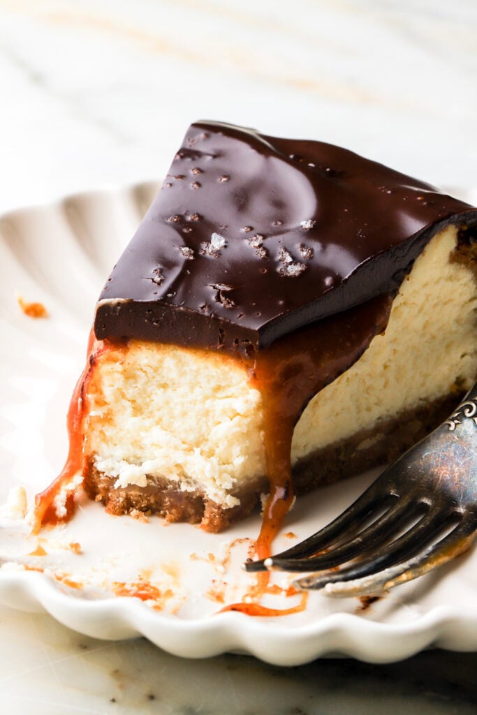 slice of millionaire cheesecake on a plate with a bite taken out