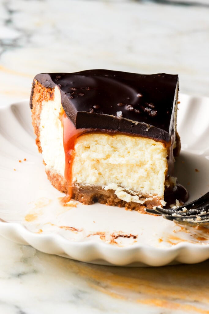 slice of millionaire cheesecake on a plate with a bite taken out