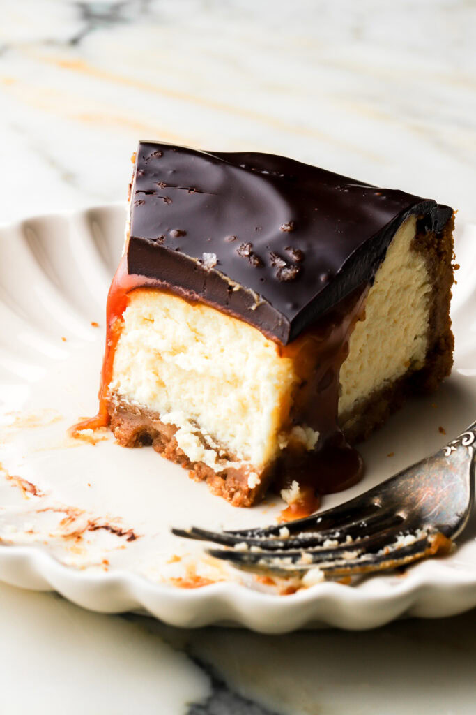 slice of millionaire cheesecake on a plate with a bite taken out