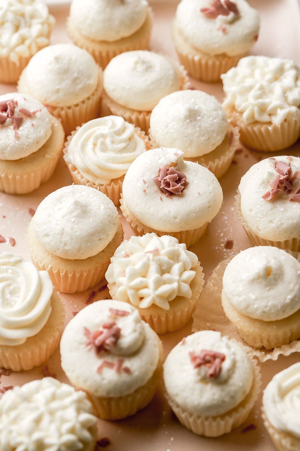 mini cupcakes frosted with white frosting and ruby chocolate swirls