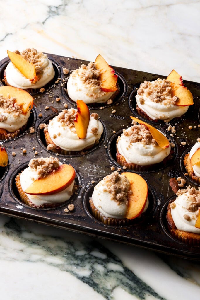 cupcakes topped with streusel and slice of peach