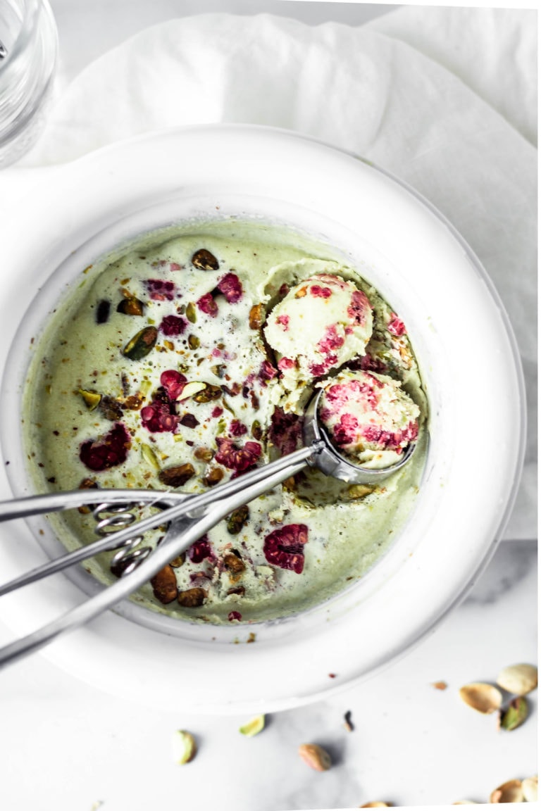 raspberry pistachio ice cream in ice cream maker and scooper