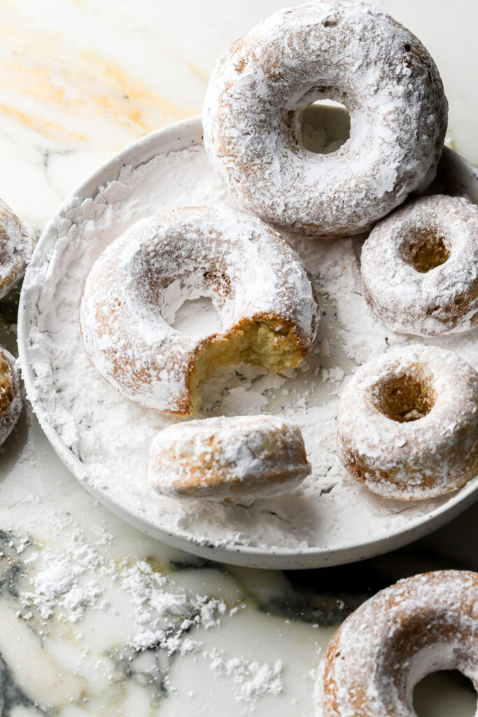 powdered sugar donuts on a plate with sugar
