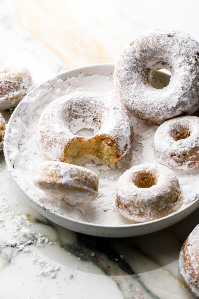 powdered sugar donuts on a plate with sugar