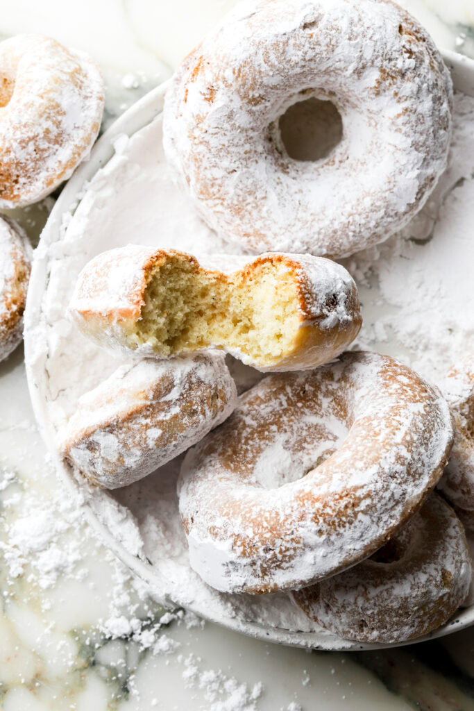 powdered sugar donuts on a plate with sugar