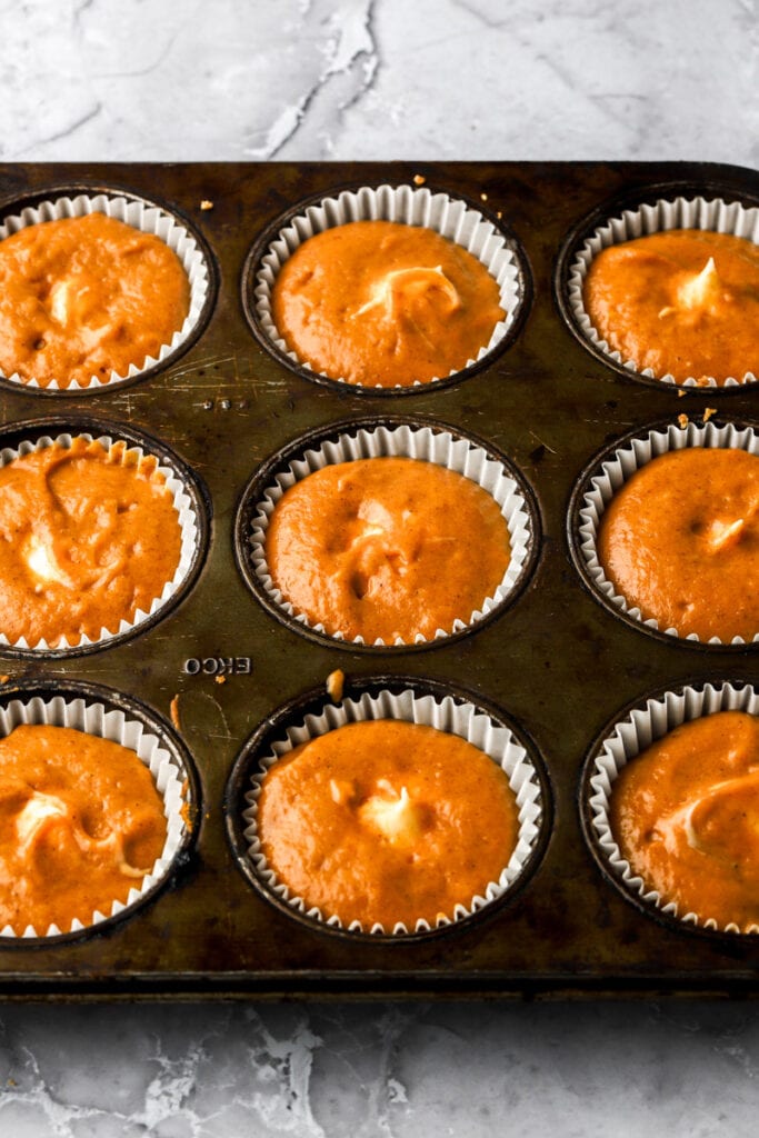 cupcake batter in liners with pipe cheesecake filling