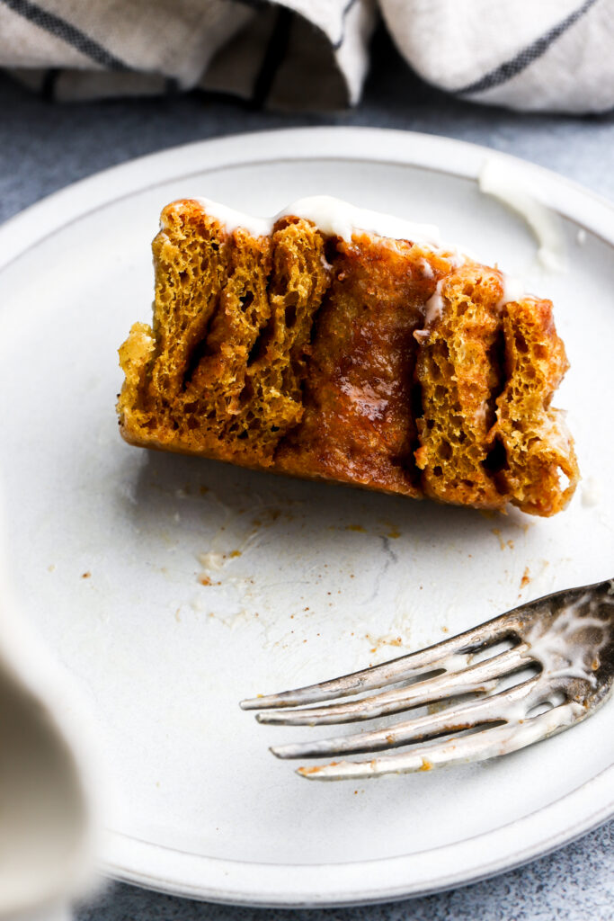 side view of a half eaten pumpkin cinnamon roll showing its gooey center