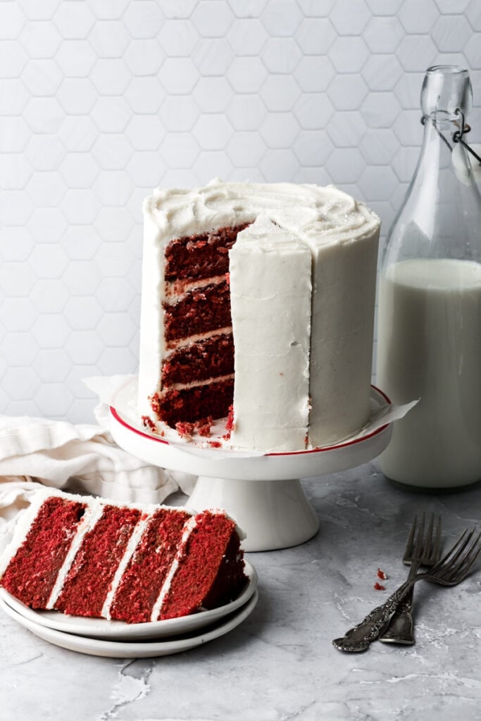 cake on a cake stand with the slices being cut