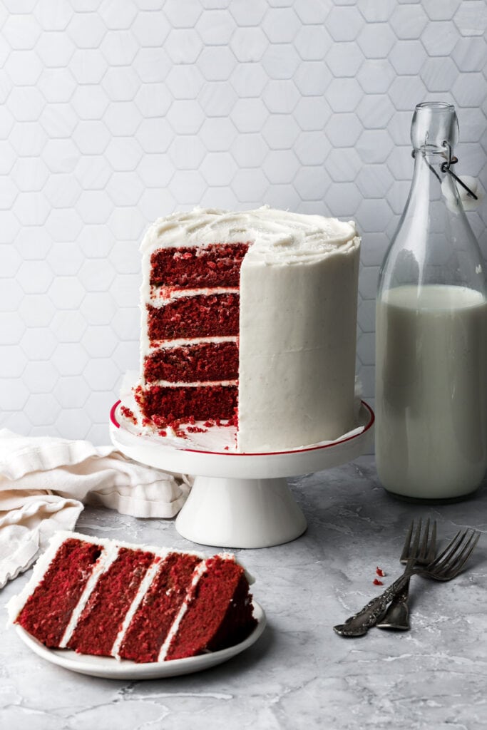 red velvet cake on a cake stand with a slice on a plate