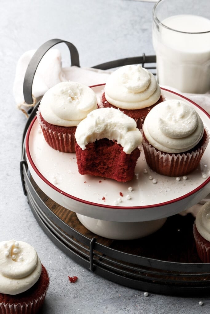 five red velvet cupcakes frosted with cream cheese frosting and bite taken out