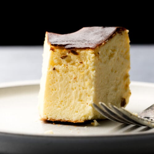 san sebastian cheesecake slice on a plate with a bite taken out